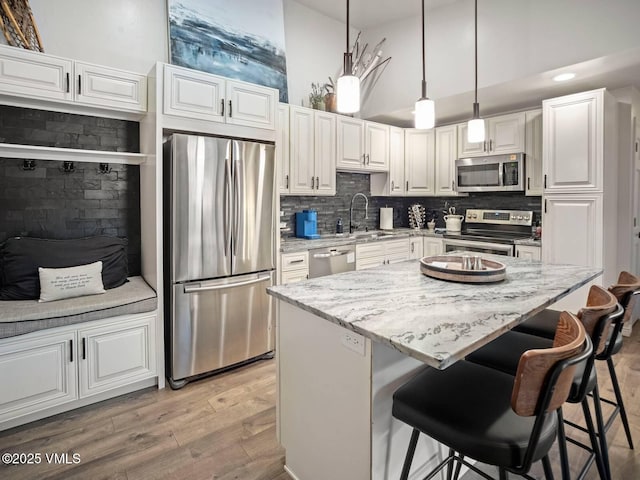 1061 W Beaver Creek Blvd Unit F-203, Avon, CO 81620 - kitchen with appliances with stainless steel finishes, light wood-style flooring, a breakfast bar, a kitchen island, and white cabinets