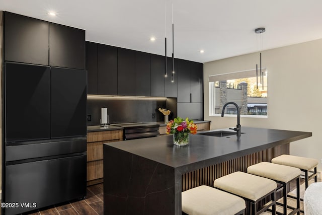 684 W Lionshead Cir Unit 302, Vail, CO 81657 - kitchen with dark countertops, dark cabinetry, an island with sink, pendant lighting, and recessed lighting