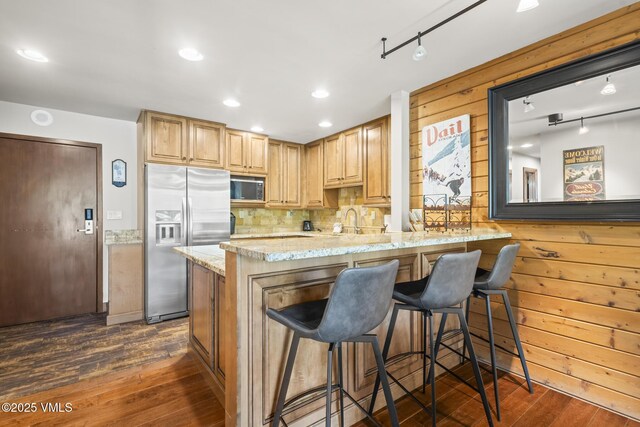 1100 N Frontage Rd W Unit 2504, Vail, CO 81657 - kitchen featuring stainless steel appliances, light stone counters, dark wood-type flooring, track lighting, and wooden walls
