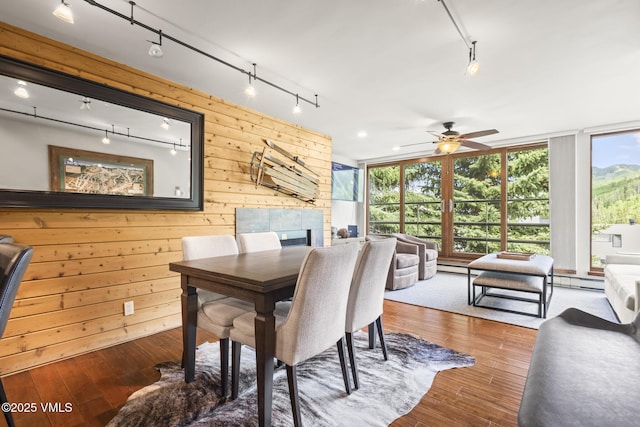 1100 N Frontage Rd W Unit 2504, Vail, CO 81657 - dining area with track lighting, a fireplace, wood walls, hardwood / wood-style flooring, and a ceiling fan