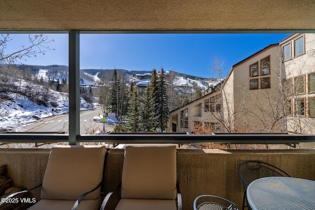 snow covered back of property featuring a mountain view