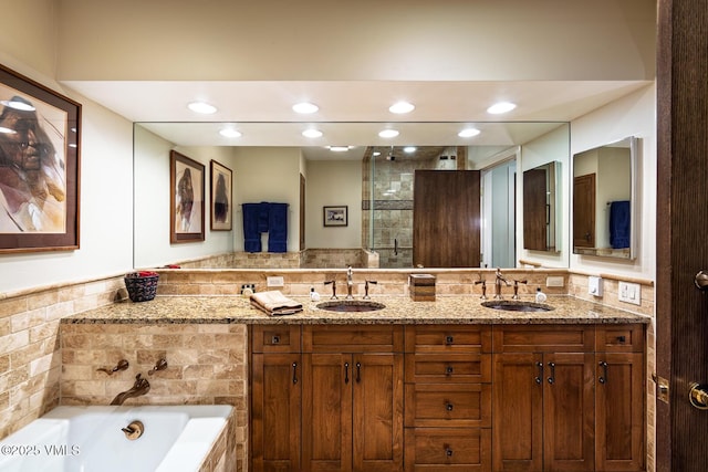 bathroom with a garden tub, recessed lighting, double vanity, and a sink