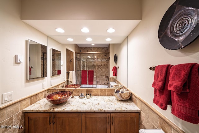 full bath with recessed lighting, a wainscoted wall, tile walls, and a stall shower