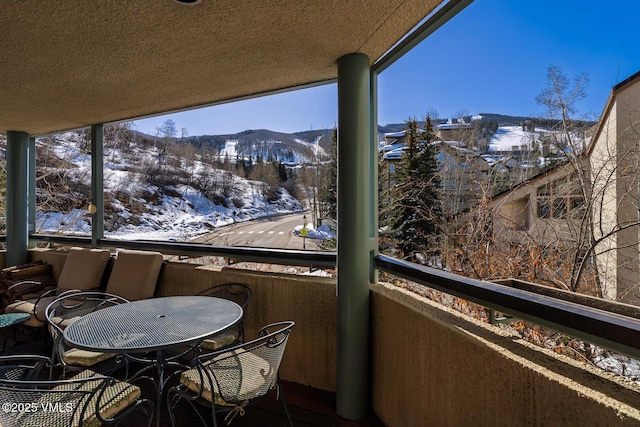 snow covered back of property featuring a mountain view