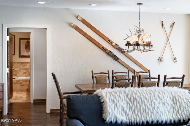 dining space featuring a chandelier, recessed lighting, wood finished floors, and a textured wall