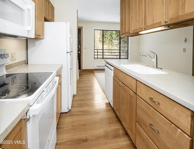 kitchen with light wood-type flooring, light countertops, a sink, and white appliances