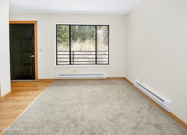 spare room featuring a baseboard heating unit, carpet, baseboards, wood finished floors, and a baseboard radiator