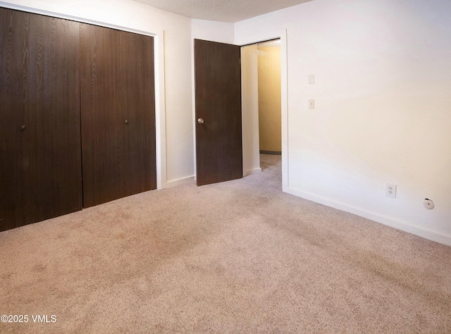 unfurnished bedroom with a closet, carpet floors, and baseboards