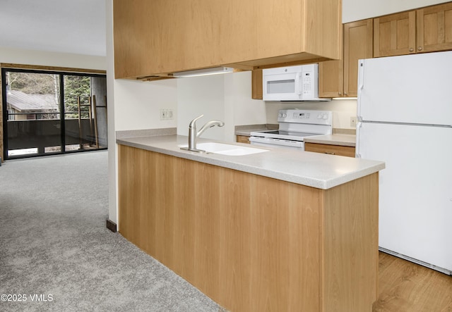 kitchen with white appliances, light countertops, light carpet, a sink, and a peninsula