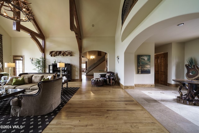 foyer featuring arched walkways, wood finished floors, high vaulted ceiling, baseboards, and stairs