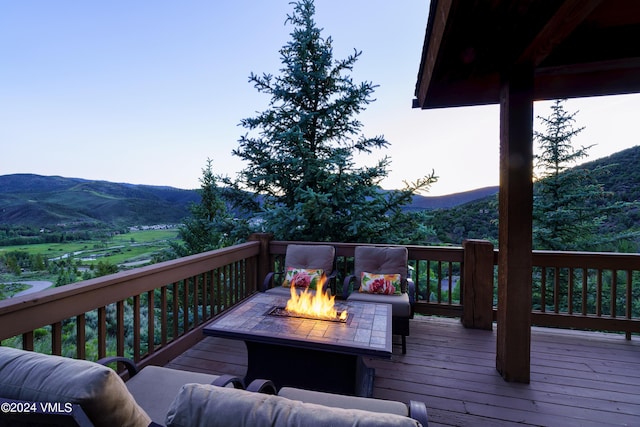 wooden deck with a fire pit and a mountain view