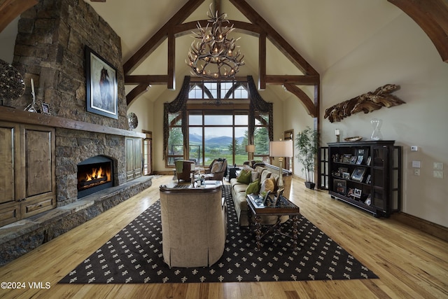 living area featuring wood finished floors, a notable chandelier, a fireplace, high vaulted ceiling, and beam ceiling