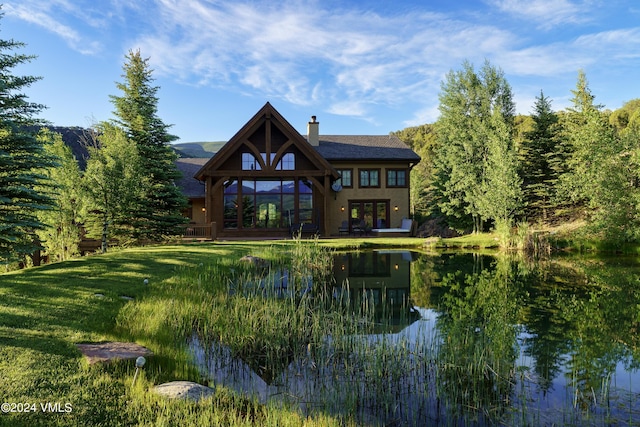 back of property featuring a water view, a yard, and a chimney