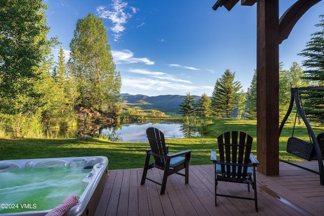 wooden terrace with a lawn, a water and mountain view, and hot tub deck surround