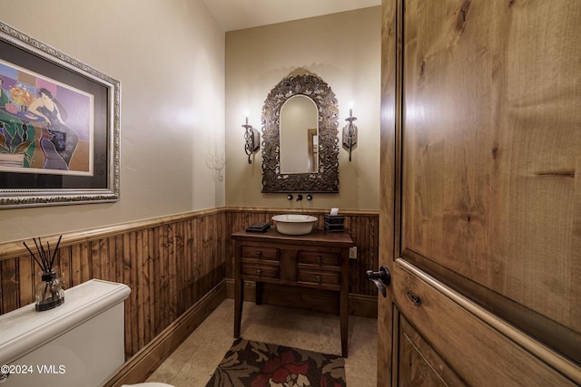 bathroom with wainscoting, vanity, toilet, and wooden walls