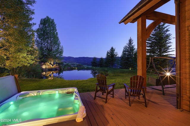 wooden terrace with a lawn, a water and mountain view, and hot tub deck surround