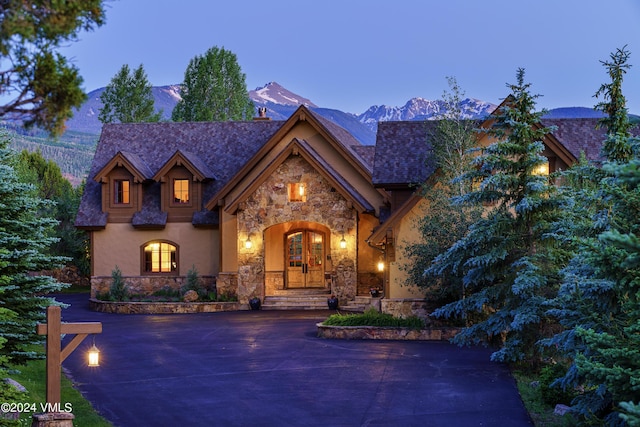 view of front of home featuring stone siding, concrete driveway, a mountain view, and stucco siding