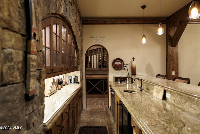 wine area with wet bar, beverage cooler, a sink, and stone tile floors