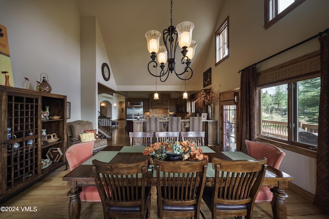 dining room featuring arched walkways, a notable chandelier, light wood-style flooring, a high ceiling, and baseboards