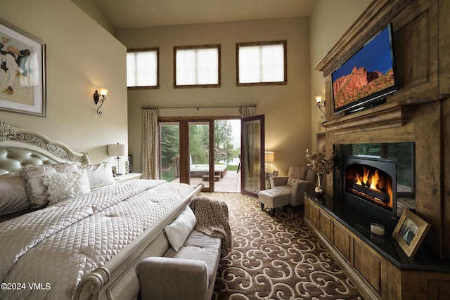 carpeted bedroom featuring access to exterior, a high ceiling, french doors, and a high end fireplace