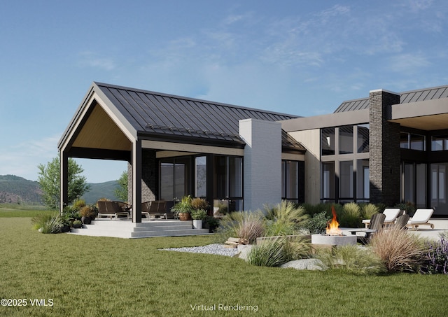 rear view of house with a mountain view, a yard, and a fire pit