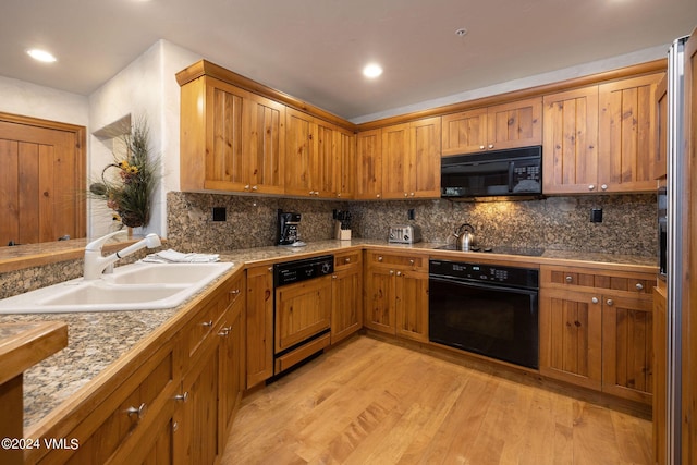 kitchen featuring sink, backsplash, black appliances, and light wood-type flooring