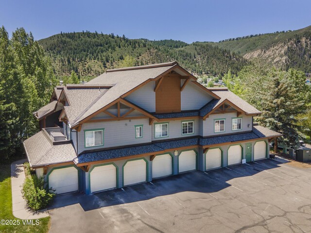 205 Crazy Horse Pt Unit 205, Edwards, CO 81632 - view of front of home with a wooded view, roof with shingles, a mountain view, and a garage