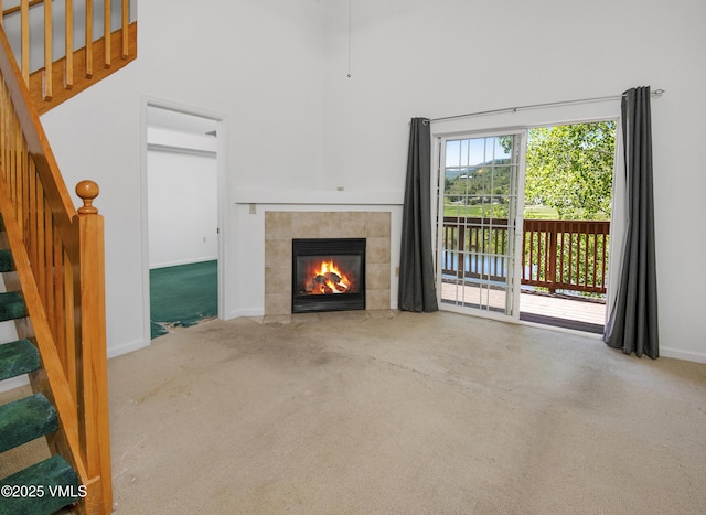 205 Crazy Horse Pt Unit 205, Edwards, CO 81632 - unfurnished living room featuring carpet flooring, stairway, a fireplace, a towering ceiling, and a water view