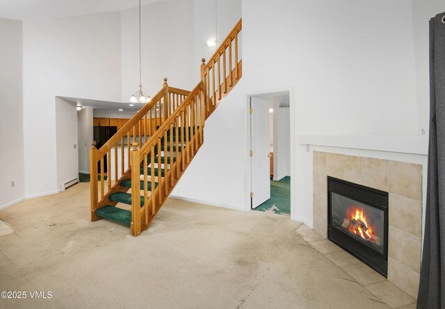 205 Crazy Horse Pt Unit 205, Edwards, CO 81632 - staircase with a towering ceiling, carpet, a tiled fireplace, a baseboard heating unit, and a chandelier