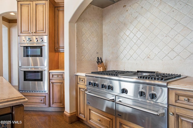 312 Holden Rd, Beaver Creek, CO 81620 - kitchen with stainless steel double oven, arched walkways, light countertops, and brown cabinets