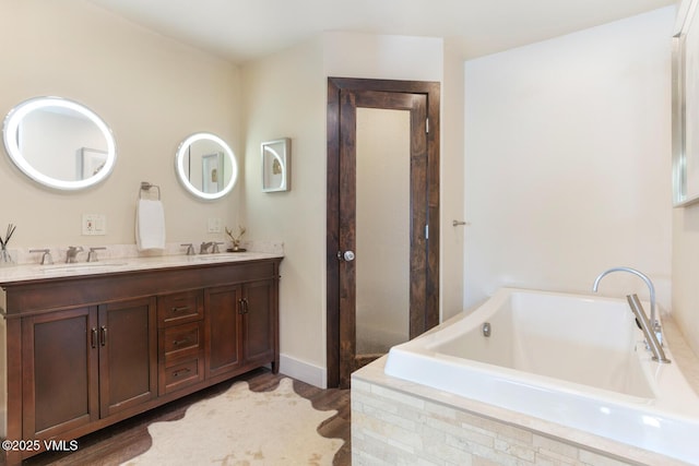 full bathroom featuring double vanity, a garden tub, and a sink