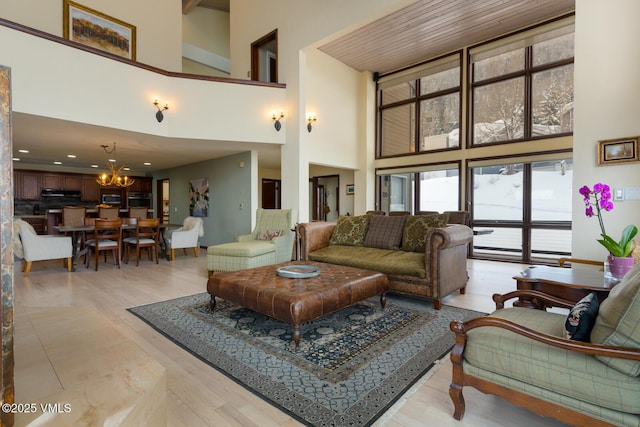 living area featuring light wood finished floors, an inviting chandelier, and a towering ceiling