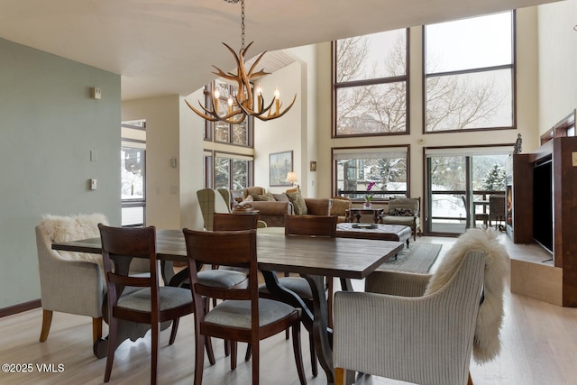 dining space with light wood finished floors, a notable chandelier, and a high ceiling