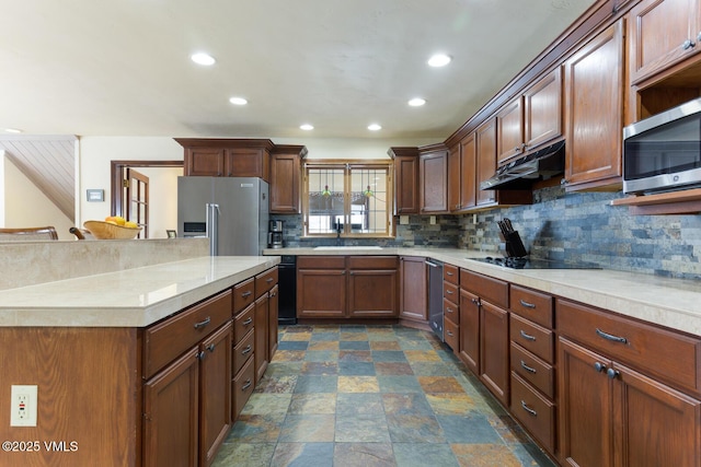 kitchen with under cabinet range hood, a sink, backsplash, appliances with stainless steel finishes, and light countertops