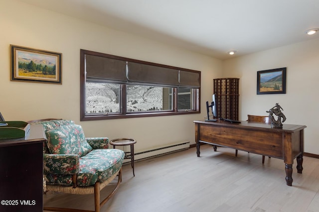 office featuring a baseboard heating unit, baseboards, and light wood-type flooring