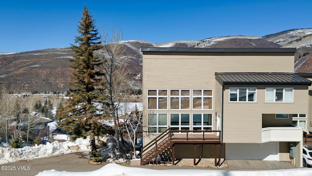 rear view of property featuring stairway, a mountain view, metal roof, and a standing seam roof