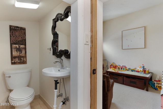 bathroom with toilet, baseboards, and a sink