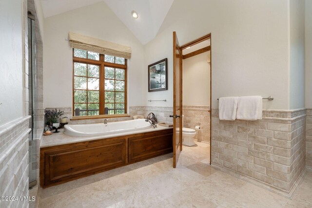 bathroom with lofted ceiling, tile walls, toilet, and a bathing tub