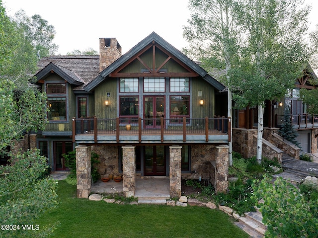 rear view of house featuring a wooden deck, a patio area, french doors, and a lawn