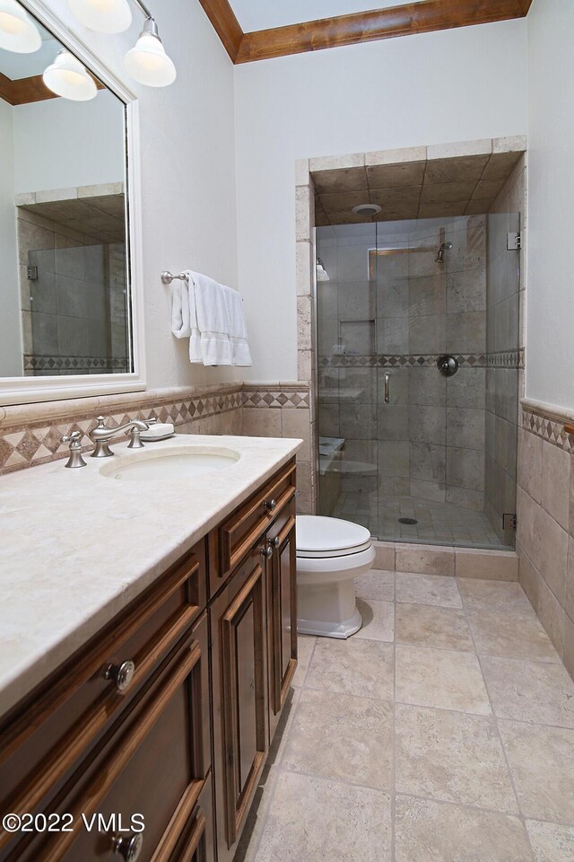 bathroom featuring vanity, a shower with door, tile walls, and toilet