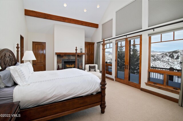 bedroom featuring multiple windows, a fireplace, a mountain view, and light carpet