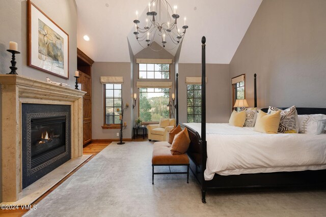 bedroom featuring a chandelier, light hardwood / wood-style floors, and high vaulted ceiling