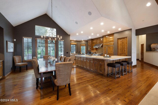 dining space featuring dark wood-type flooring, high vaulted ceiling, and a chandelier