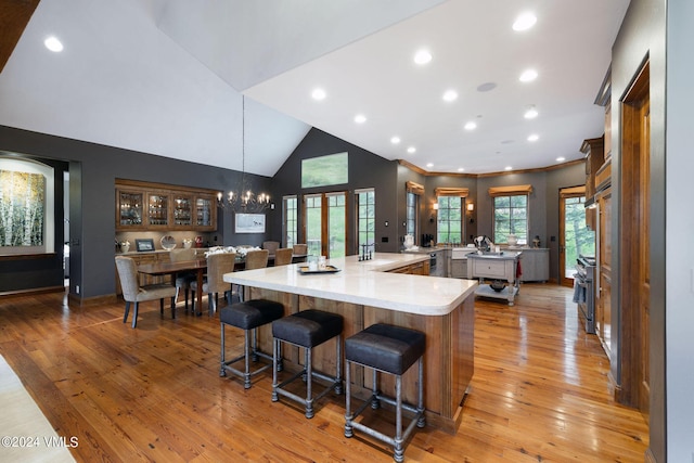 kitchen with an inviting chandelier, a kitchen breakfast bar, hanging light fixtures, light wood-type flooring, and a spacious island