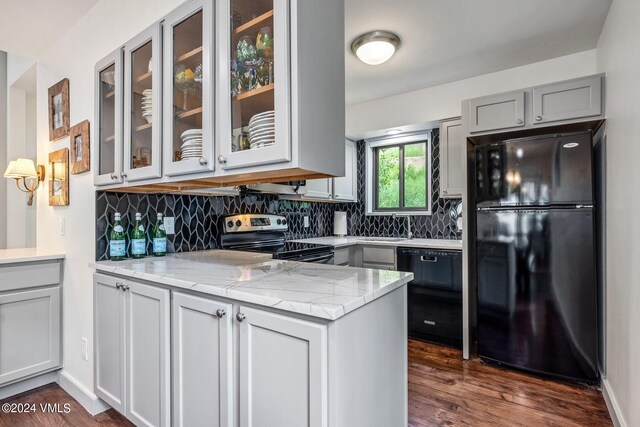 kitchen featuring light stone counters, dark wood-type flooring, tasteful backsplash, and black appliances