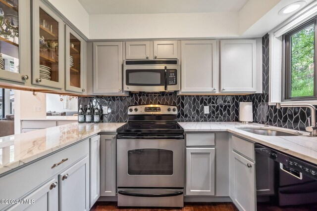 kitchen featuring light stone counters, sink, backsplash, and stainless steel appliances