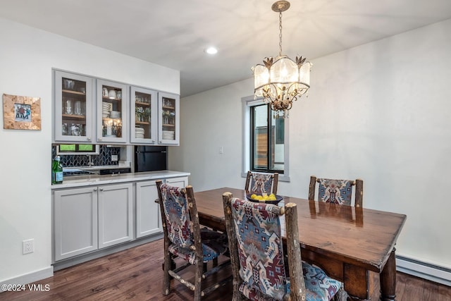 dining room featuring a baseboard radiator, dark wood-type flooring, and a notable chandelier