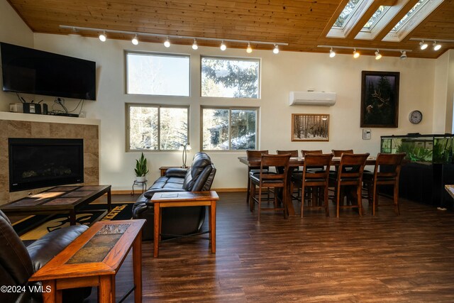 living room with a tile fireplace, an AC wall unit, dark hardwood / wood-style floors, a skylight, and track lighting