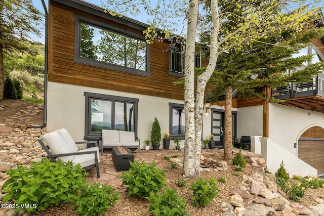 5780 Wildridge Rd E Unit A, Avon, CO 81620 - view of front of house with stucco siding, an outdoor living space with a fire pit, a patio area, and a balcony