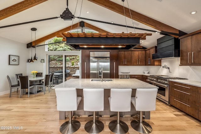5780 Wildridge Rd E Unit A, Avon, CO 81620 - kitchen featuring high quality appliances, a sink, custom range hood, light wood finished floors, and backsplash